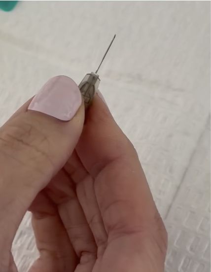 Hand holding a small needle syringe.